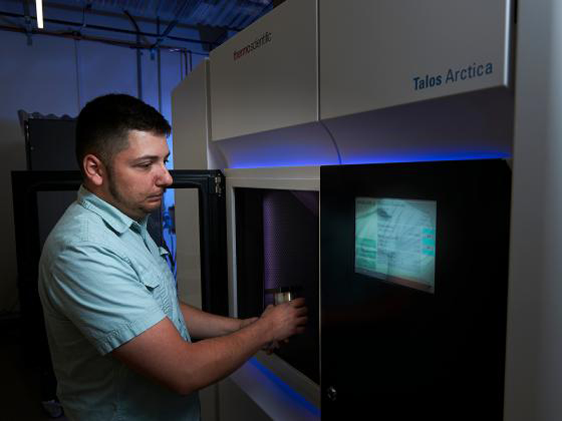 MSU graduate places a sample in a new TEM microscope